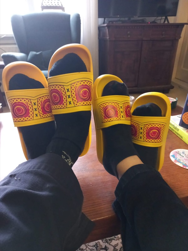Klant draagt gele zomerklompen slippers thuis op de bank
