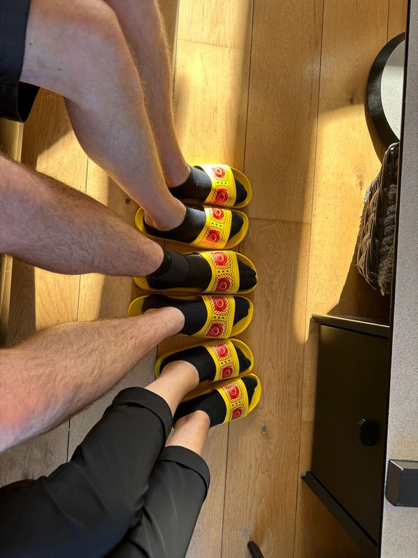 Twee klanten dragen gele zomerklompen slippers op een houten vloer