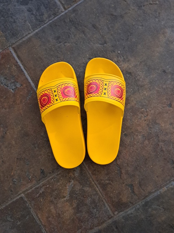 Gele zomerklompen slippers met Hollands patroon op buitentegels