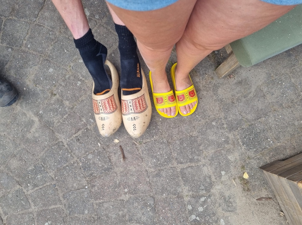 Vergelijking tussen traditionele houten klompen en gele zomerklompen slippers op straatstenen